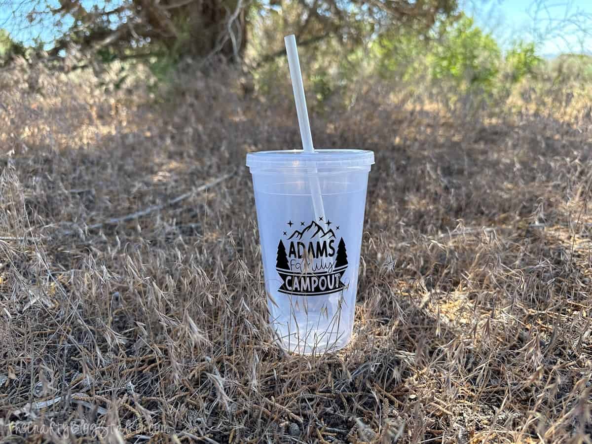 A plastic cup with a straw and a decal that reads Adams Family Campout.
