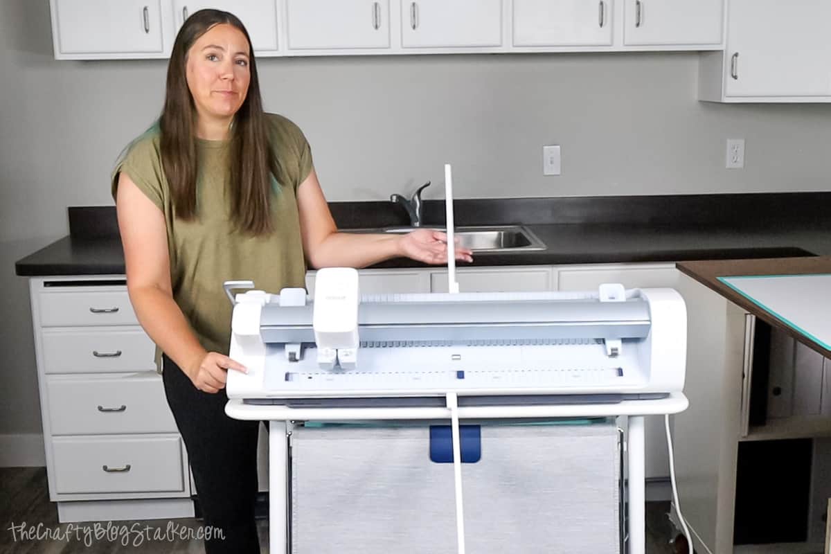 Woman standing next to the Cricut Venture deploying the support arms.