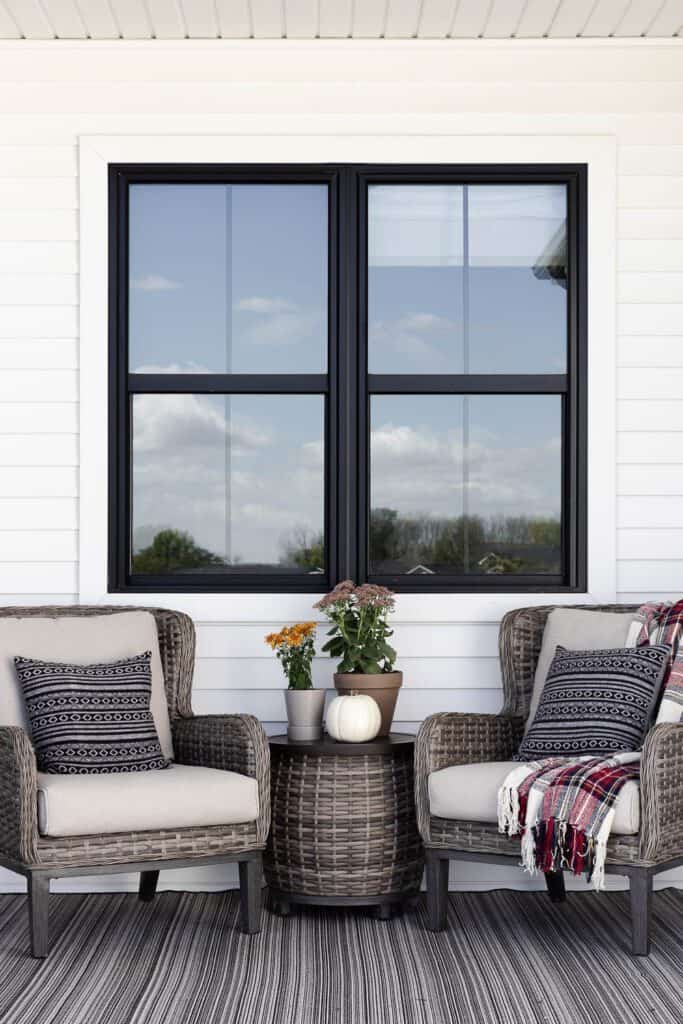 Cozy porch with wicker chairs, pillows, and fall-themed decor.