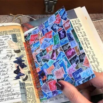 A junk journal with handwritten notes on a vintage dictionary page, decorated with stickers and a colorful collage of postage stamps on the adjacent folded page.