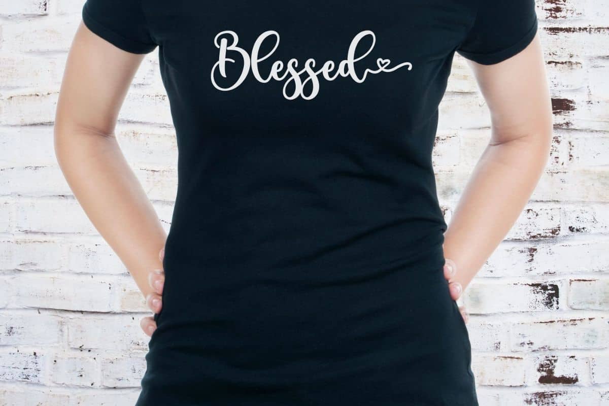 Woman wearing a black shirt with "blessed" in white script font.