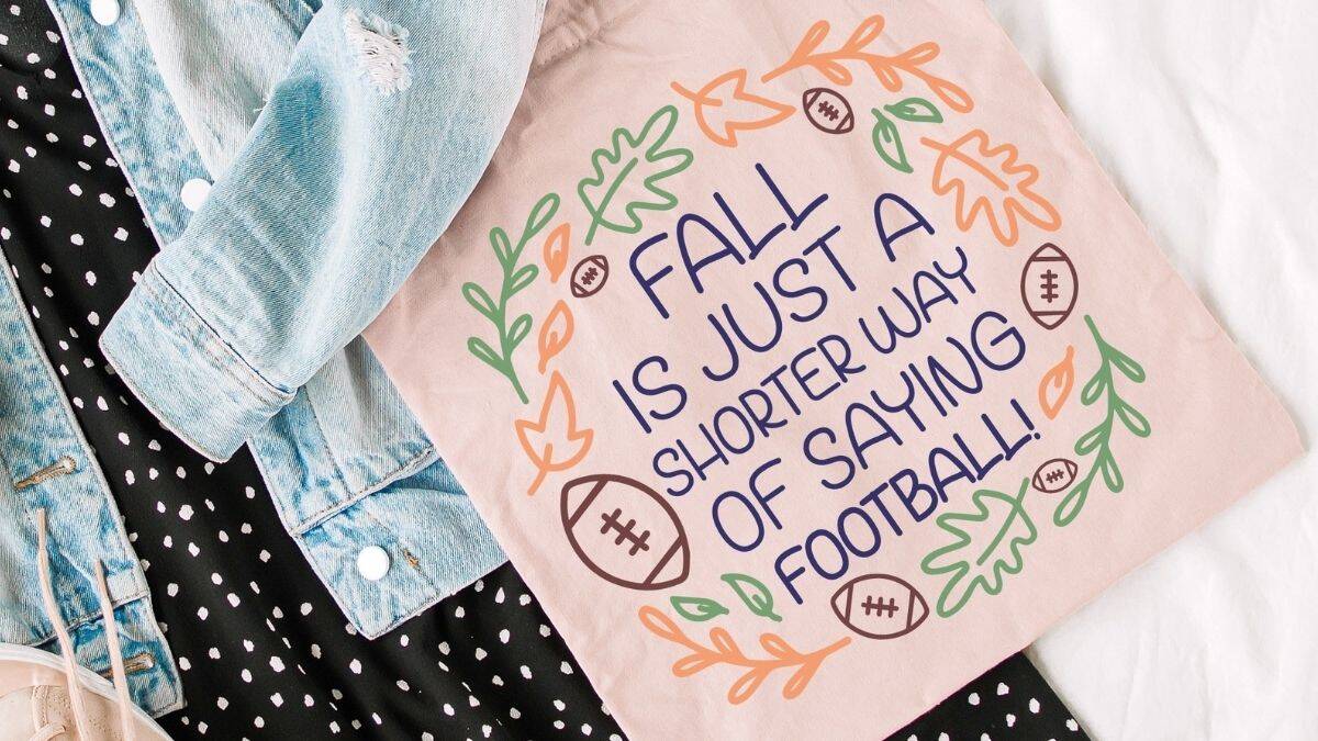 Beige tote bag with colorful fall leaves, footballs, and the phrase 