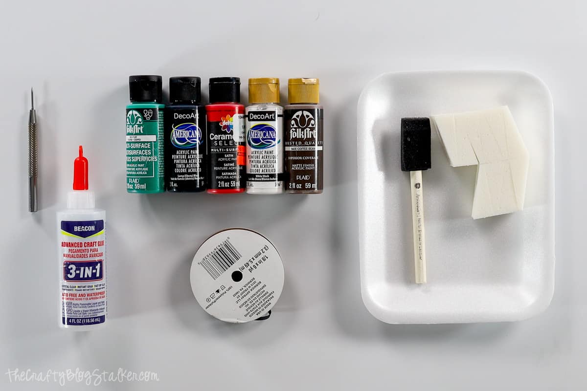 Supplies used to make project, acrylic paint, glue, ribbon, foam brushes, and an awl.