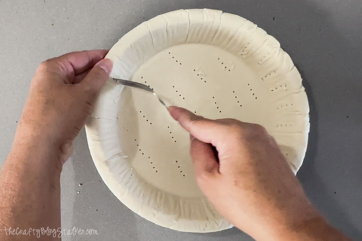Poking holes in a pie crust with a fork.