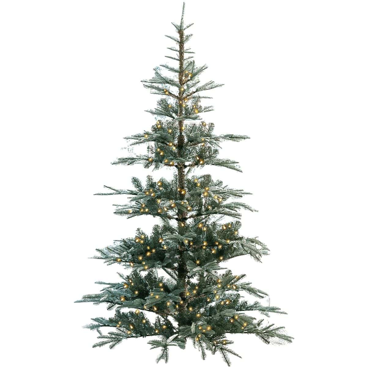 Tall artificial Christmas tree with warm white LED lights set in front of a large window with patterned curtains and natural light streaming in.