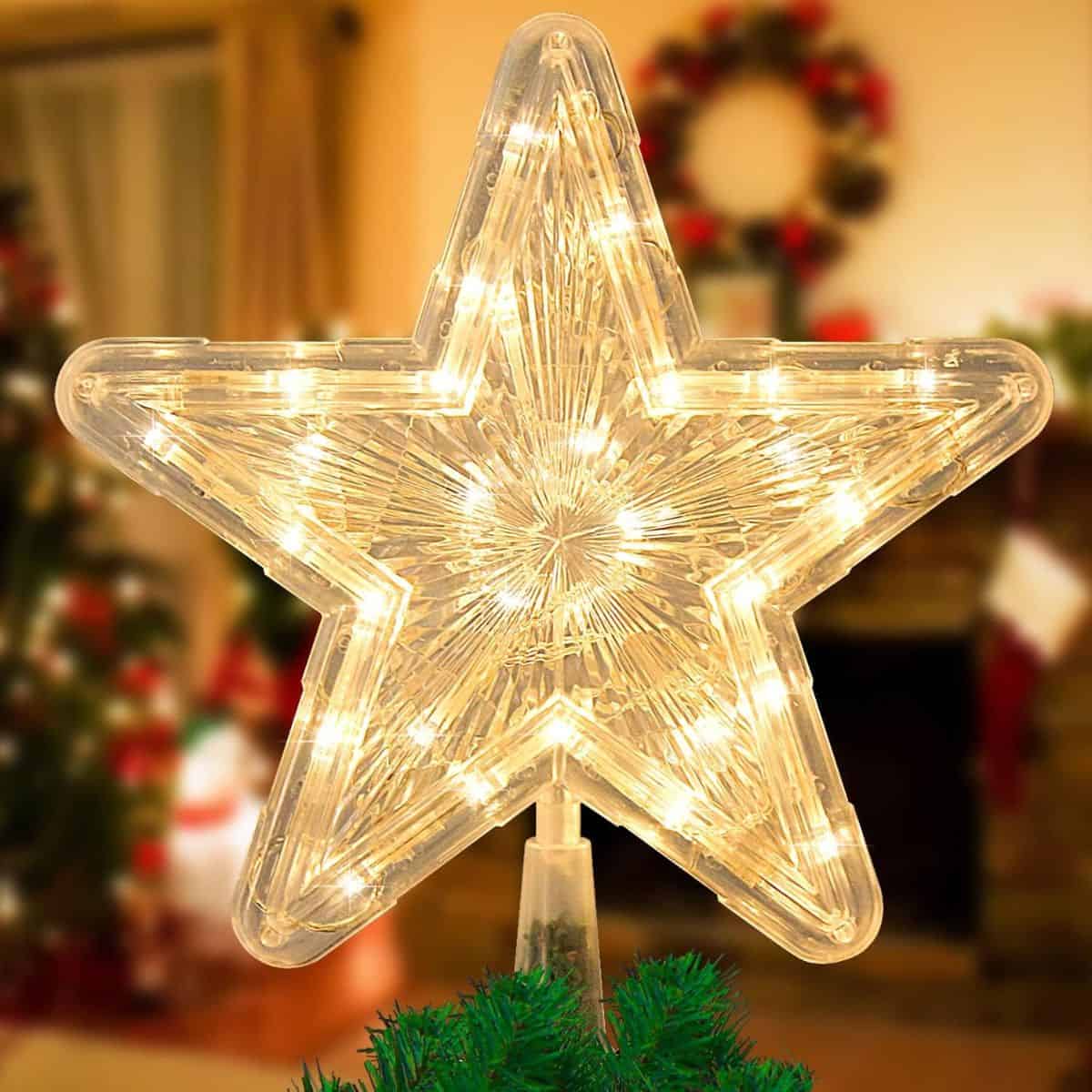 Lighted Christmas star tree topper with warm white LED lights and a clear textured design sitting on top of a green Christmas tree.