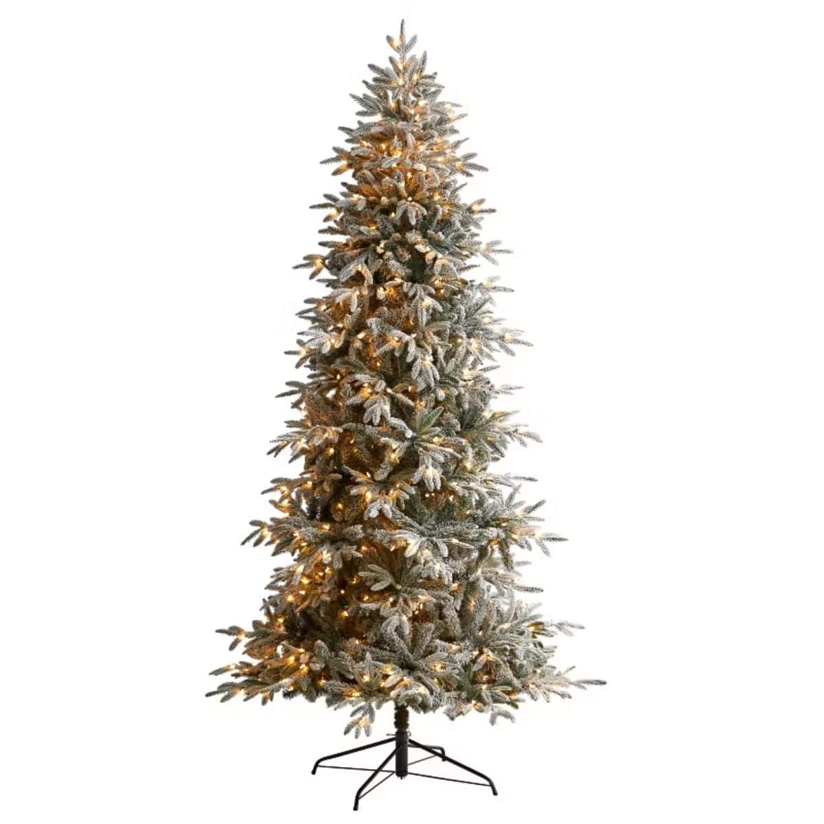 Flocked artificial spruce Christmas tree with warm white lights and realistic snow-dusted branches, standing on a black metal base.