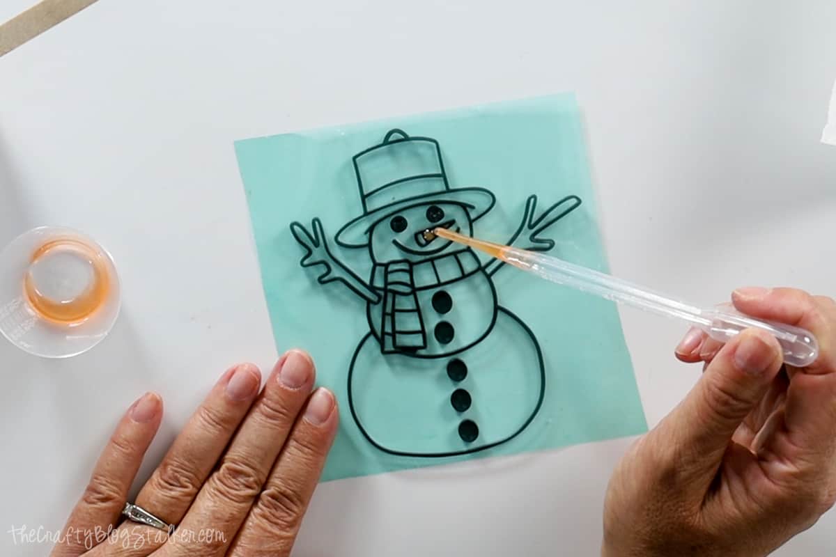 Dropping orange resin into the snowman's nose.