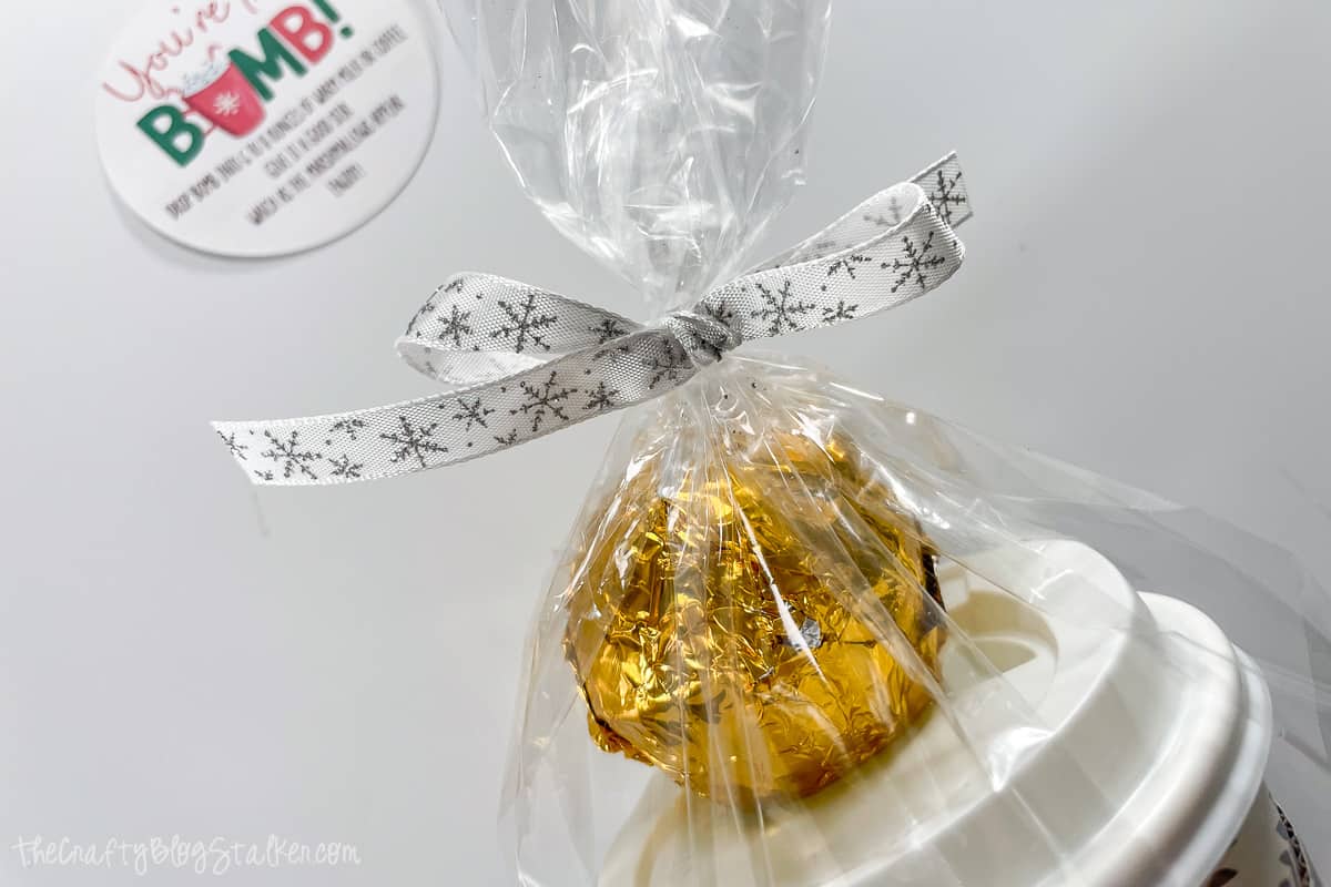 Hot chocolate bomb gift bag tied with festive ribbon.