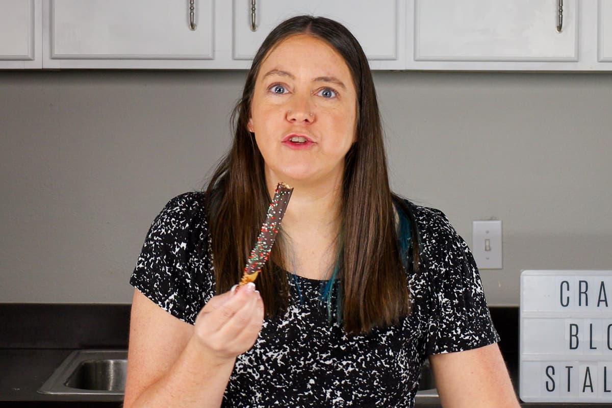 A woman eating chocolate pretzel rods.