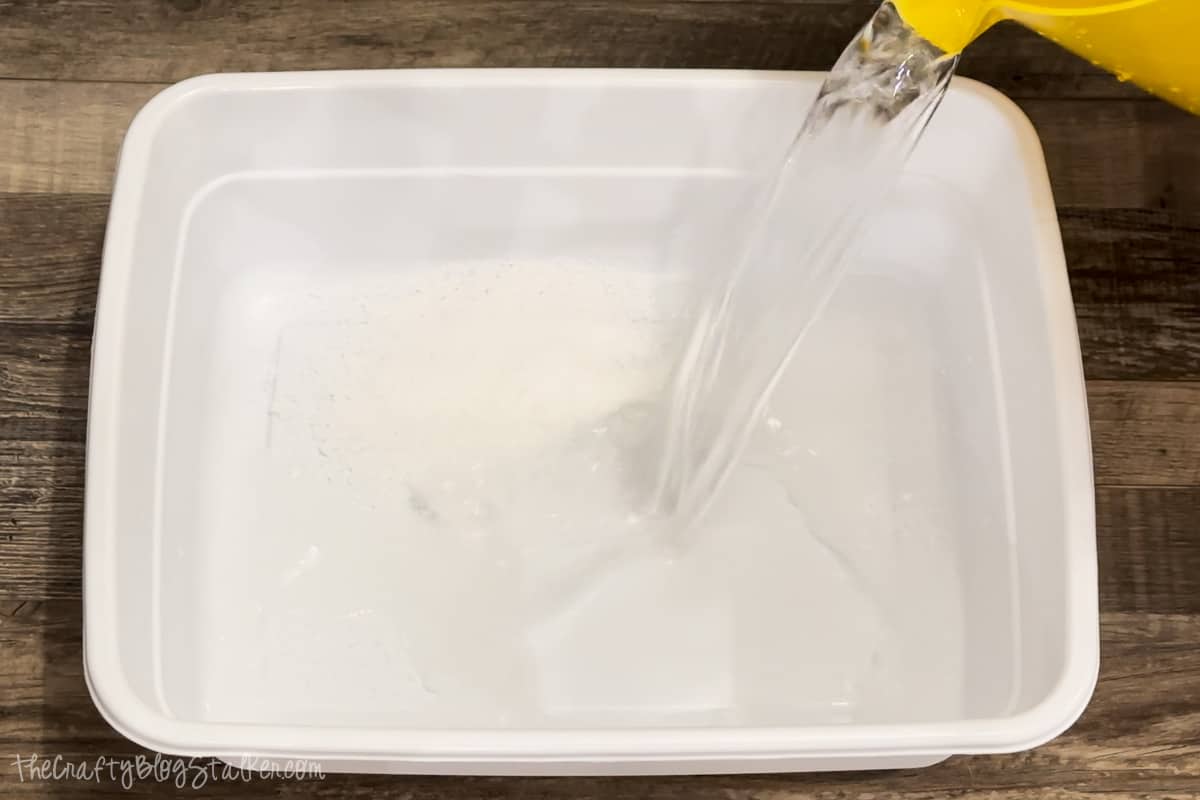 Adding warm water to the plastic bin.