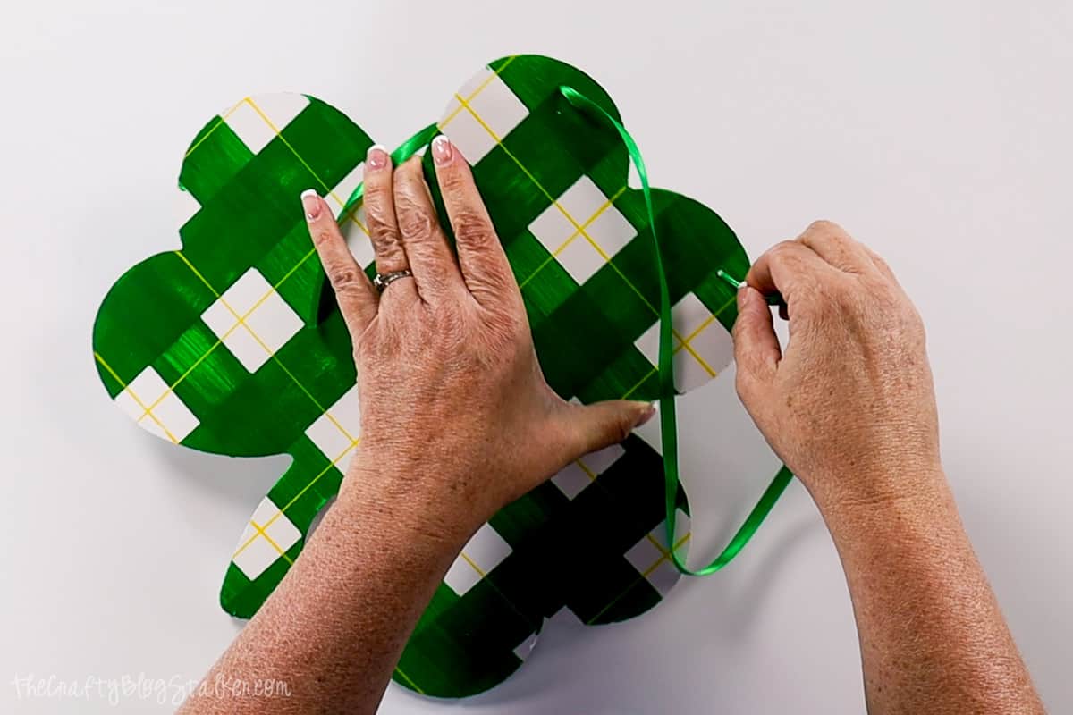 Poking the ribbon through the holes in the shamrock.