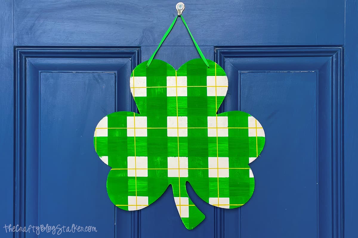 Painted plaid shamrock hanging on a front door.