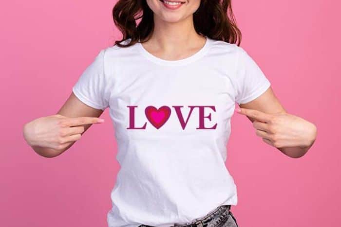 Woman pointing to her white t-shirt with a 'Love' design.