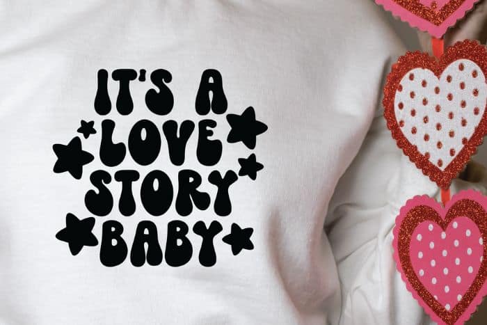 White sweatshirt with a design that reads 'It's a Love Story Baby'.