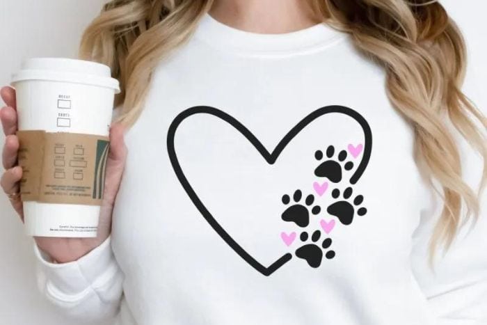 Woman wearing a white sweatshirt with a heart and paws design.