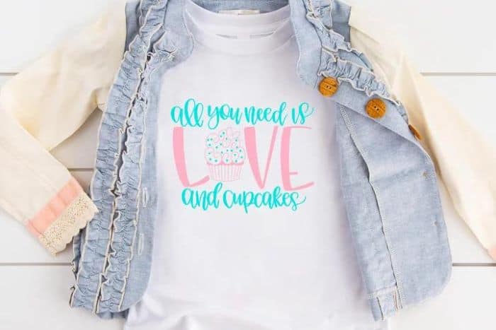 A white t-shirt with a design that reads "All You Need is Love and Cupcakes".