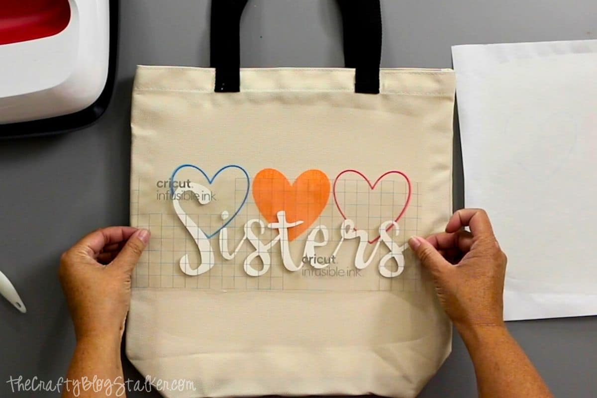 Placing the cut infusible ink sheet design on a tote bag.