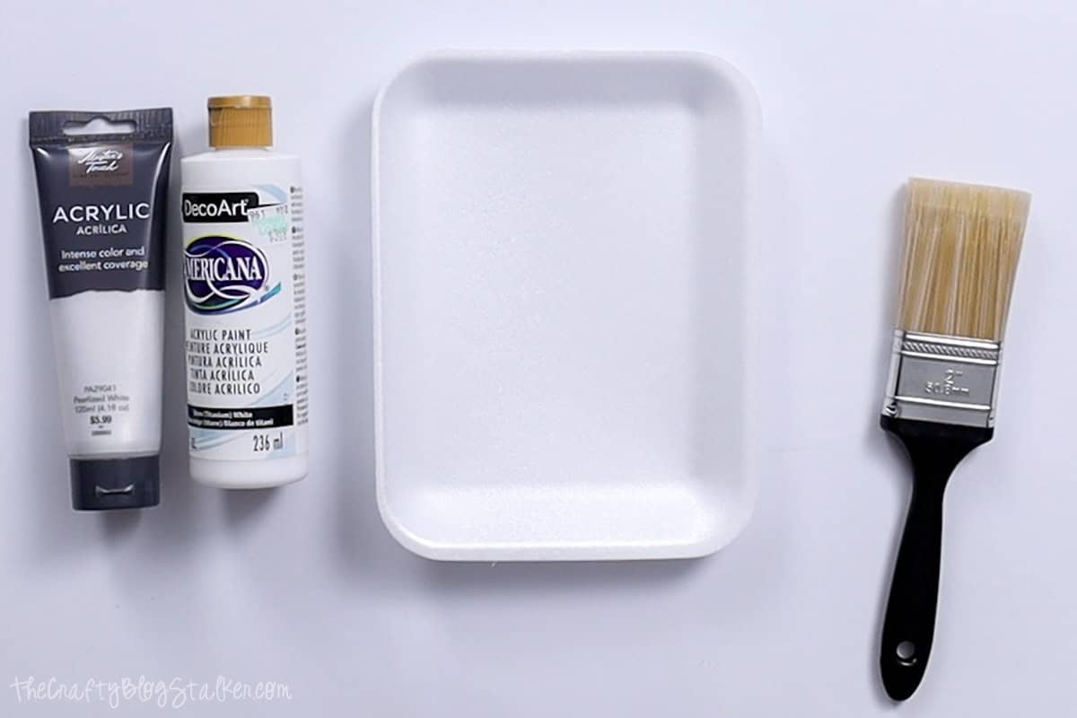 A pearl paint, white paint, paint pallet, and a paint brush.