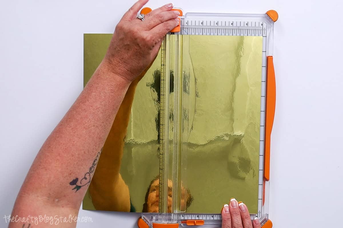 Cutting a sheet of gold vinyl in half with a paper trimmer.