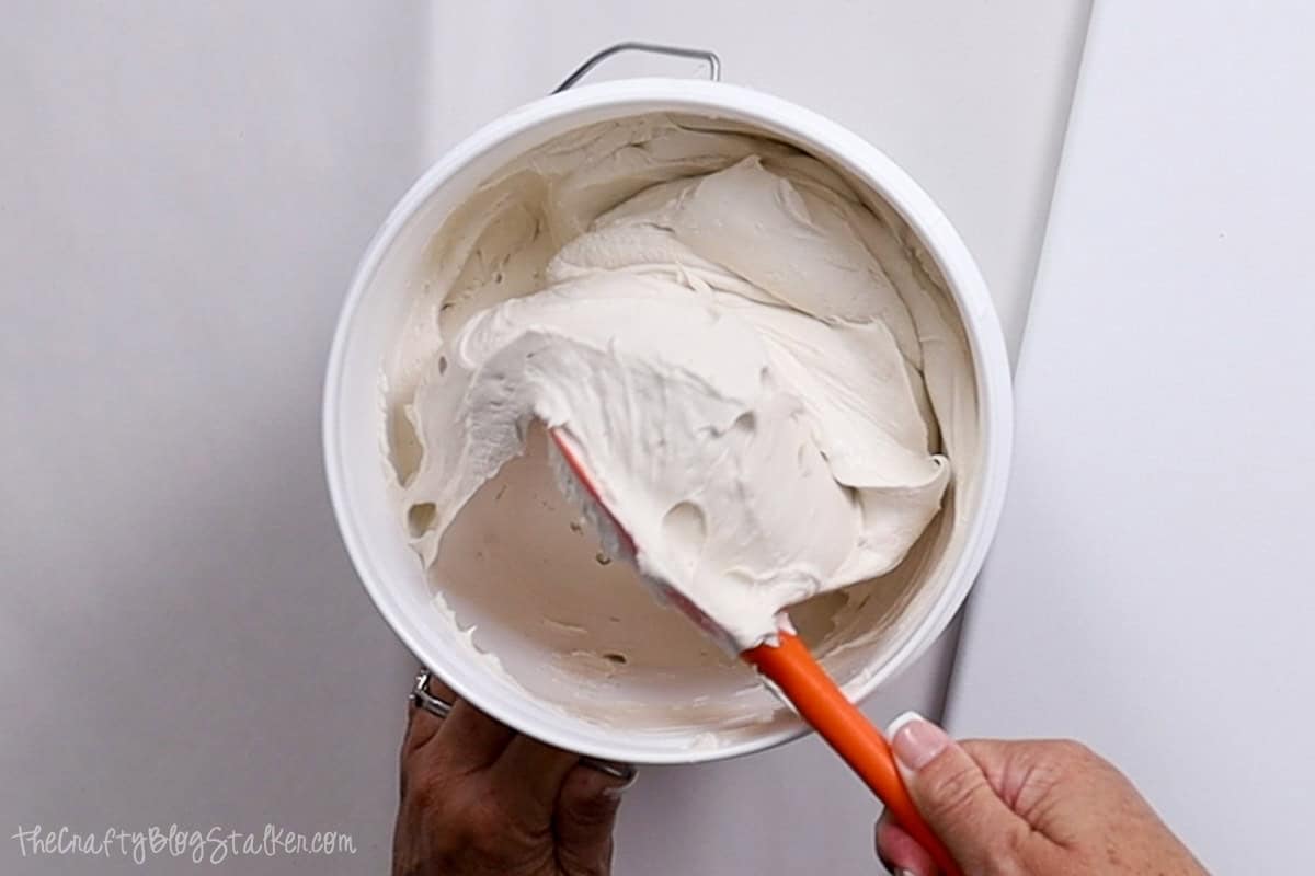 Stirring joint compound with a rubber spatula.