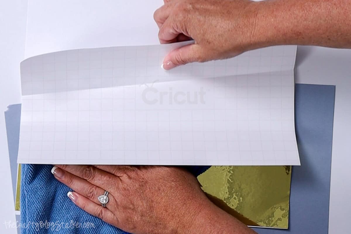 Applying vinyl to paper using a soft cloth to press it down.