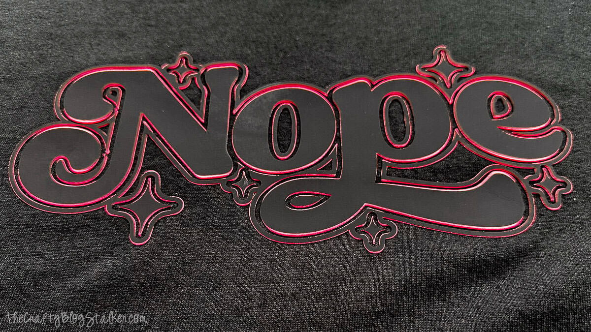 Close-up of a finished “Nope” vinyl design pressed onto a T-shirt, showing the layered outline and glossy surface.