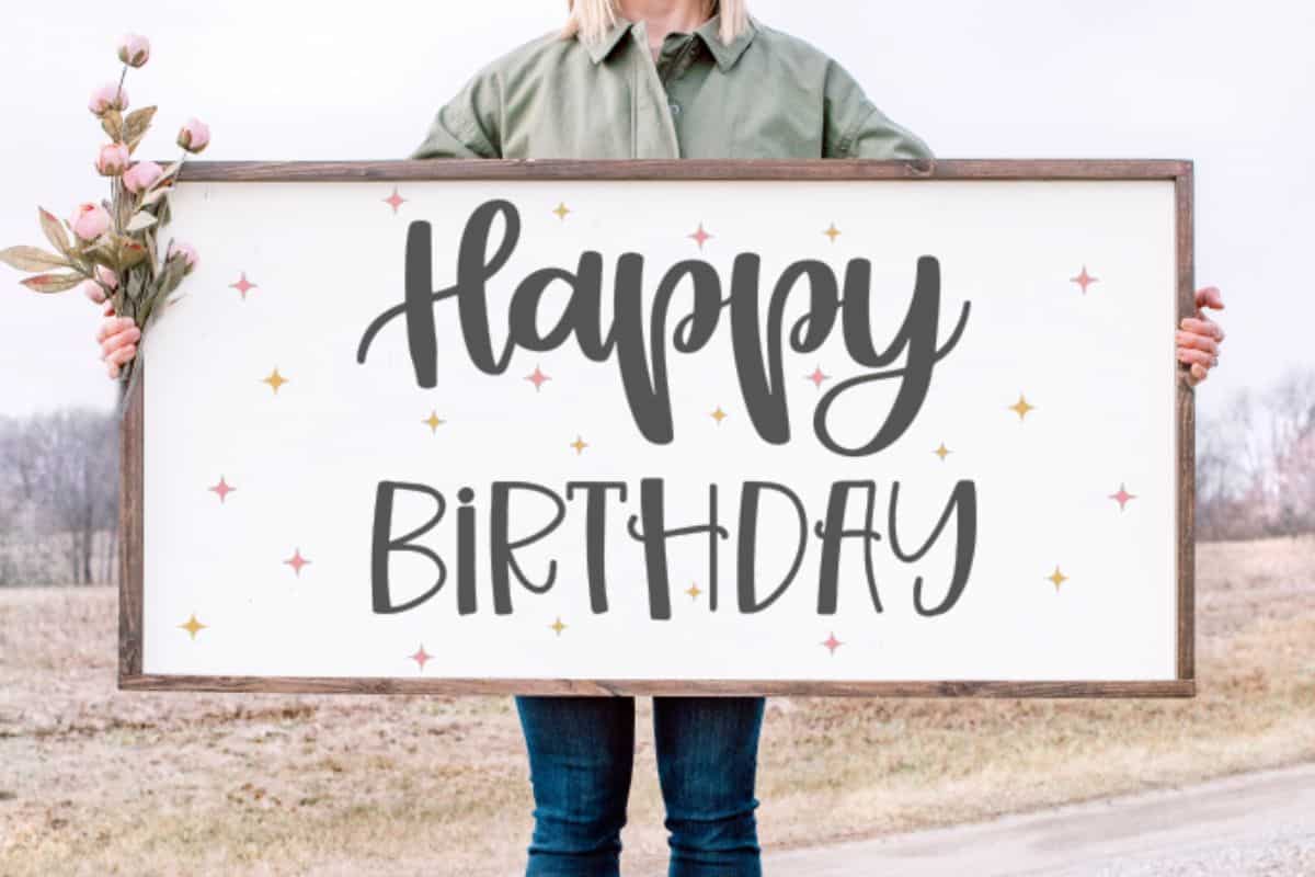 Woman holding a "Happy Birthday" sign.