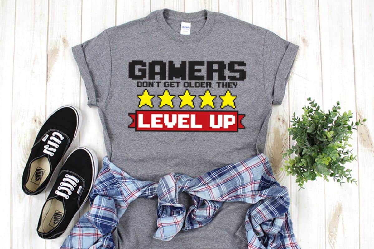 Grey t-shirt with the design 'gamers don't get older, they level up'.