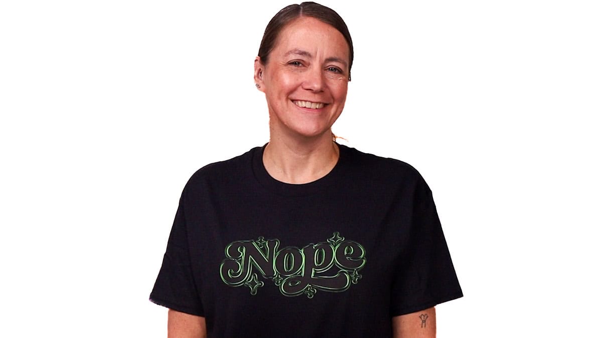 Smiling woman wearing a T-shirt featuring a bold “Nope” vinyl design centered on the front.