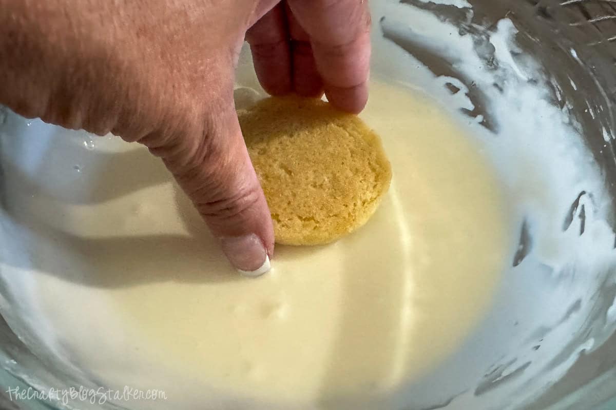 Dipping the top of the cookie in icing.