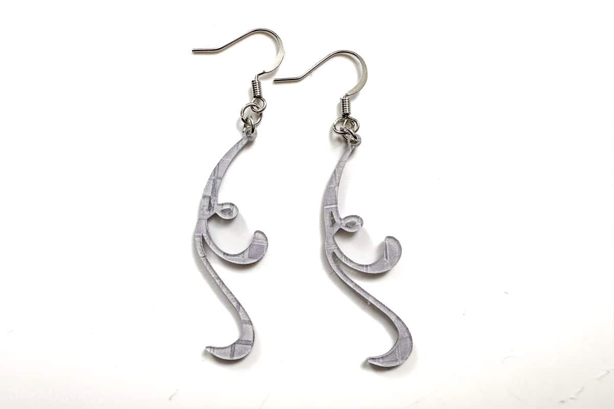 A pair of flourish earrings cut from acrylic and a laser cutter.