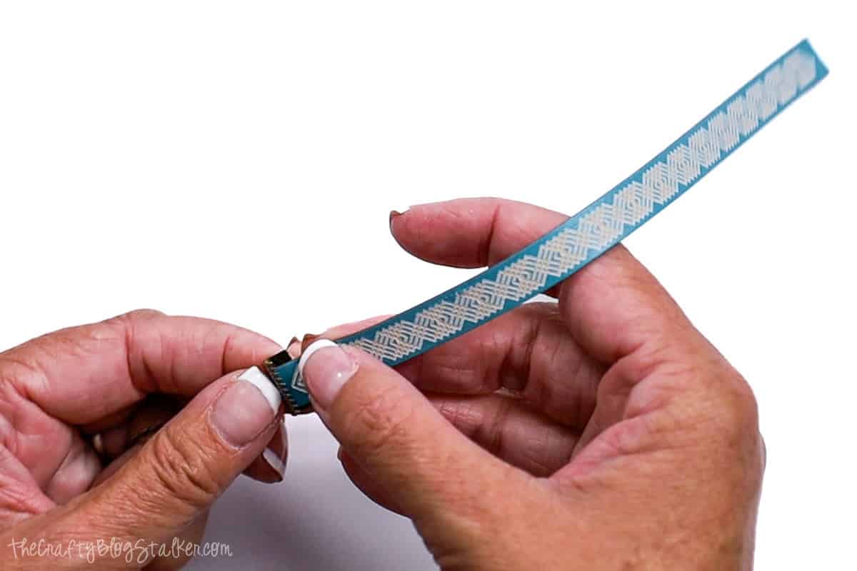 Attaching a ribbon clamp to the end of the leather bracelet.