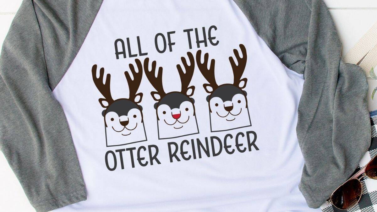 Baseball-style shirt featuring three cartoon otters with reindeer antlers and the phrase 