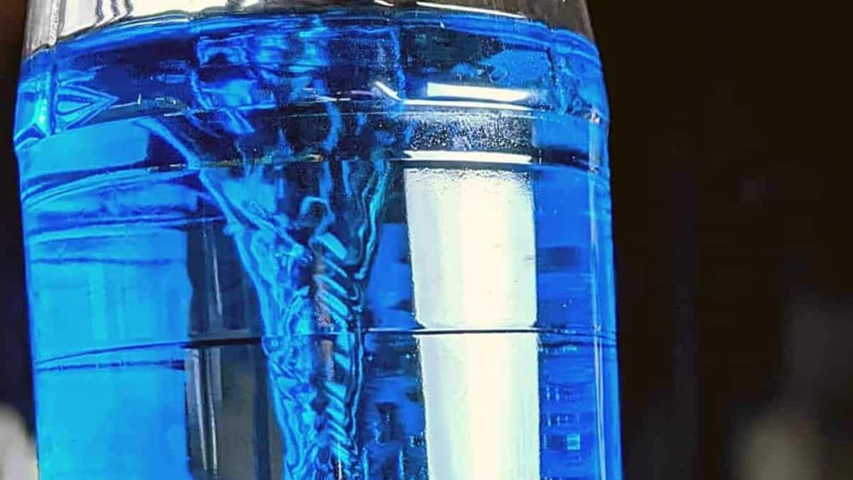 Close-up of a blue tornado-in-a-bottle experiment showing a swirling water vortex inside a clear plastic bottle.