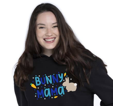 Smiling woman wearing a black hoodie featuring the phrase "Bunny Mama" in blue text with a cute bunny illustration, carrots, and colorful dots as decoration.