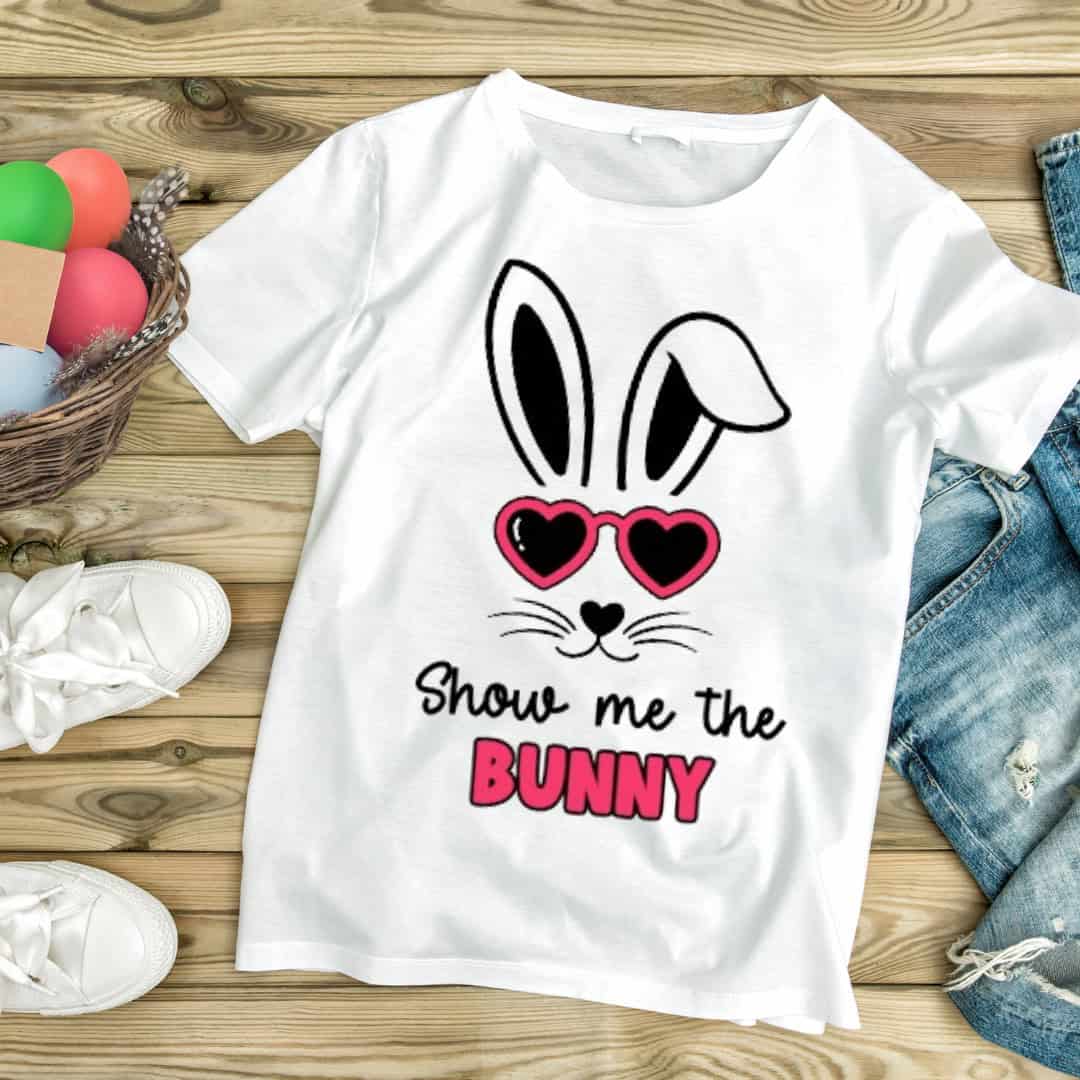 White T-shirt with a playful Easter design featuring a bunny face with heart-shaped sunglasses and the phrase "Show me the Bunny" in black and pink text.