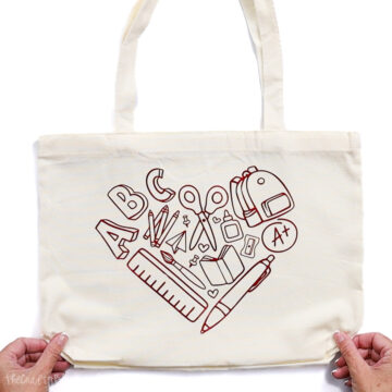 Canvas tote bag with a red foil heart-shaped design made of school supplies, including scissors, ruler, pencils, backpack, and ABC letters—ideal for teachers.