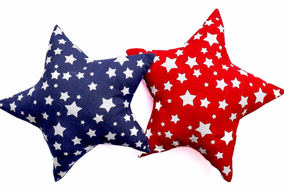 Two star-shaped throw pillows—one red and one blue—decorated with white stars, styled in a patriotic theme on a white background.