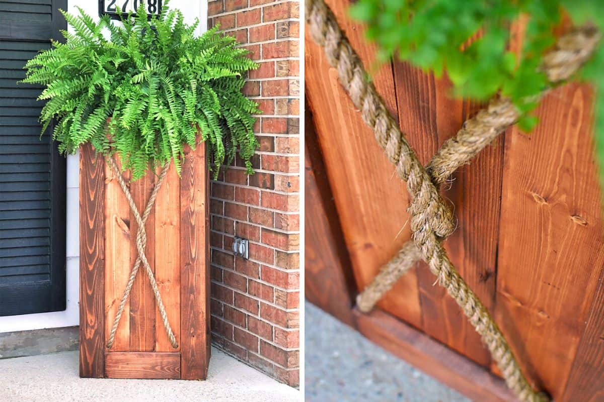 Tall wooden planter with a rich stain finish, decorated with a knotted rope in an X pattern, holding a lush green fern by a brick wall and black shutter.