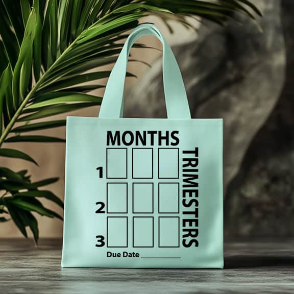 Light blue tote bag with a black pregnancy countdown chart showing months and trimesters, plus a blank line labeled "Due Date" at the bottom.