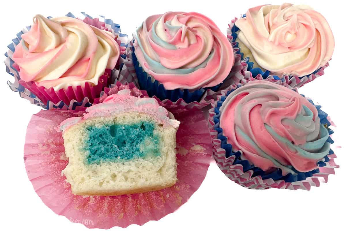 Five gender reveal cupcakes with pink, blue, and white swirled frosting; one is cut open to show a bright blue center revealing it's a boy.