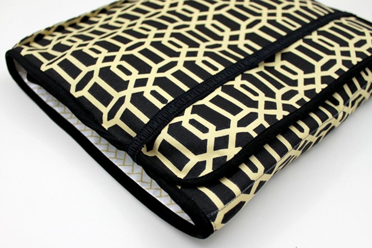 Folded on-the-go diaper changing pad with a black and beige geometric pattern, neatly stitched and compact for travel use.