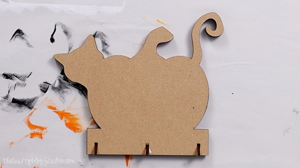 The back of the laser-cut pumpkin with a cat attached, showing notches at the bottom for assembly.