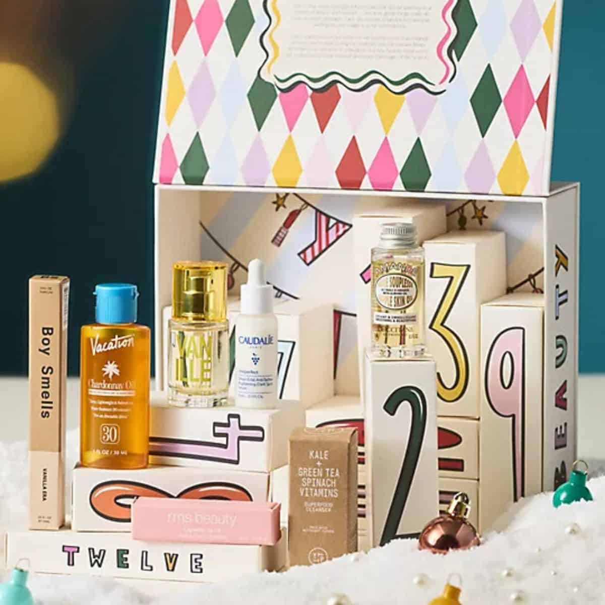 Anthropologie beauty advent calendar with numbered boxes, featuring skincare, perfume, sunscreen, and beauty products displayed in front of a festive holiday box.