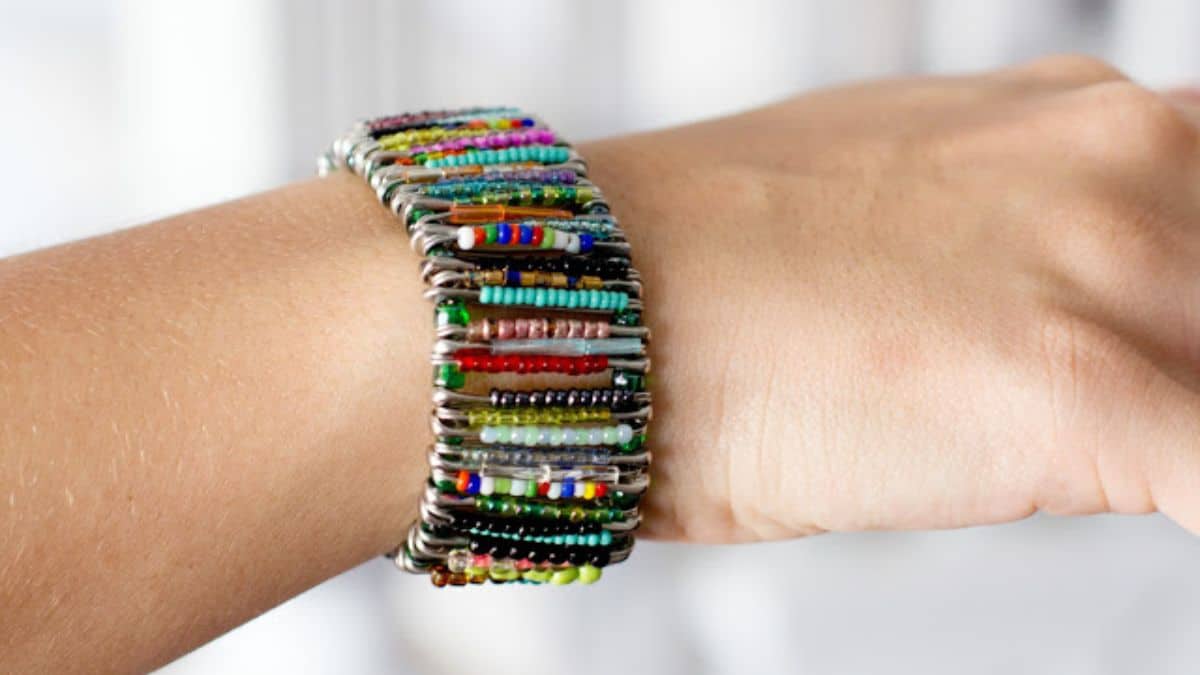 Colorful DIY safety pin bracelet with multicolored seed beads threaded onto safety pins, creating a bold and unique handmade cuff worn on the wrist.