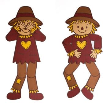 Two paper scarecrows with movable arms and legs, wearing brown hats and red shirts with yellow heart patches, posed playfully side by side.