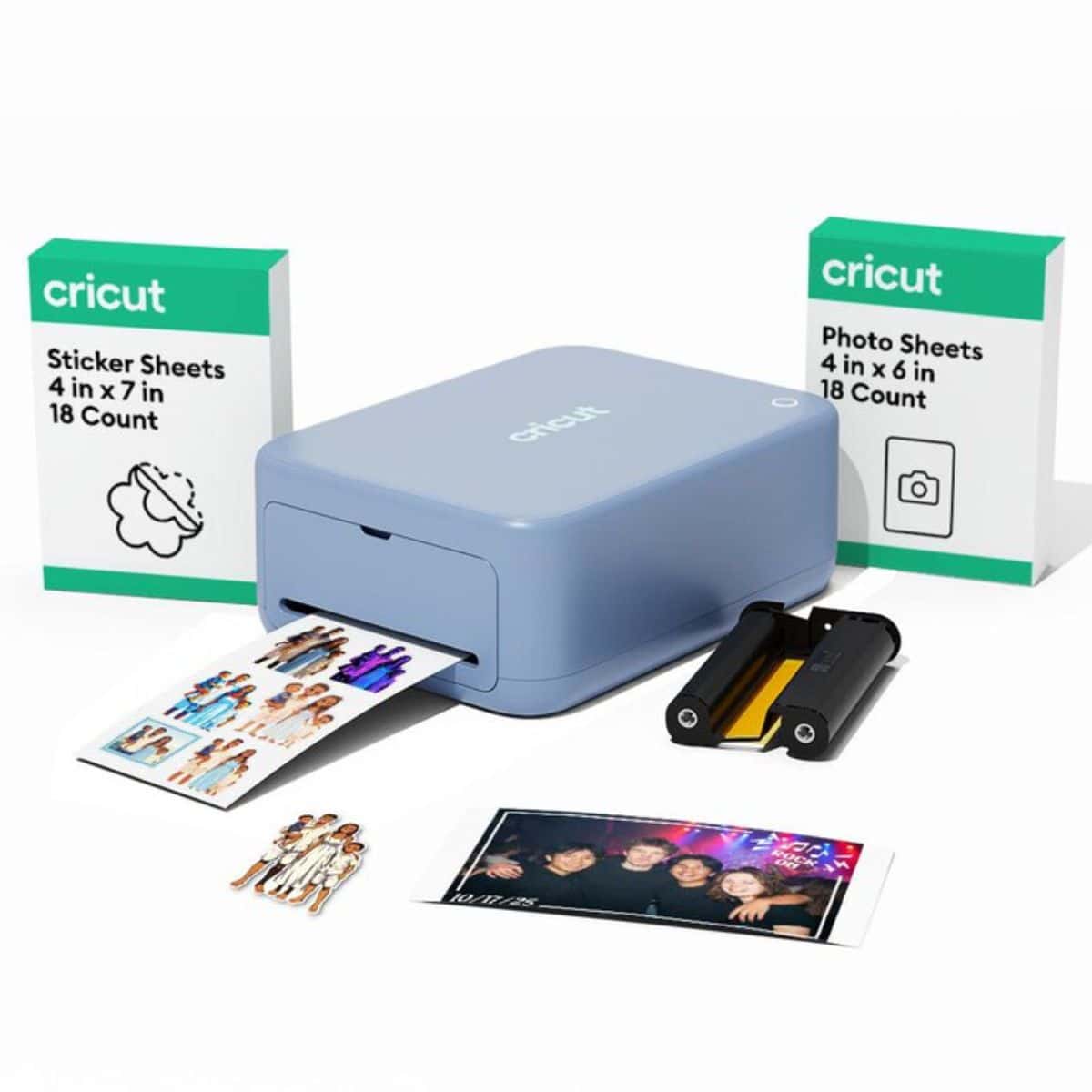 Blue Cricut StickerPix printer with sticker and photo sheets, printed photos, stickers, and a cartridge on a white background.