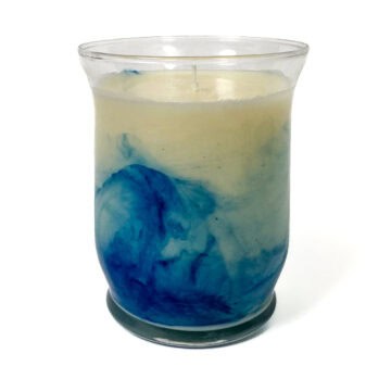A handmade soy candle in a glass jar with a blue marbled design and a single centered wick, shown against a white background.