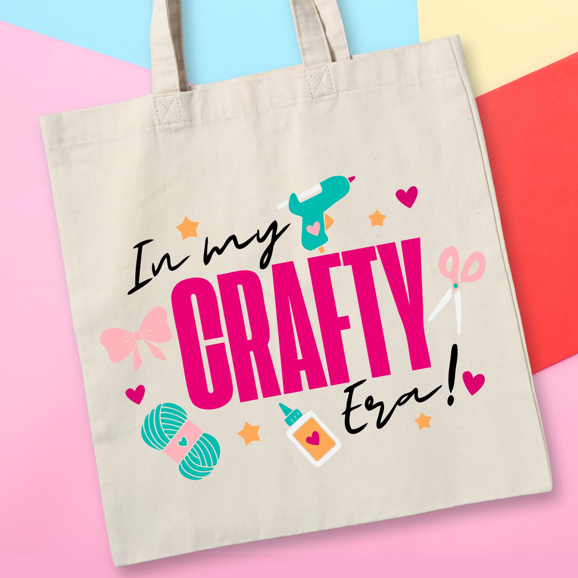 Canvas tote bag with the phrase In my crafty era and illustrated craft icons like scissors, yarn, glue, and a heat gun on a colorful background.